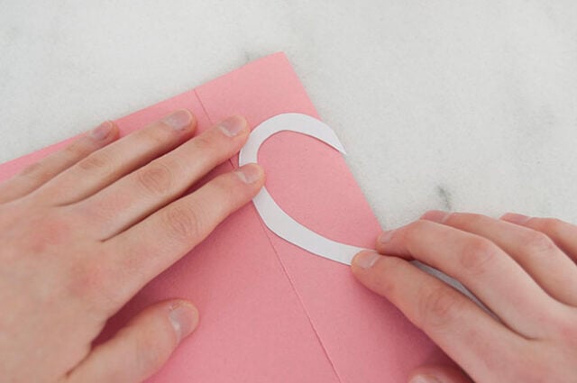Holding template onto pink paper