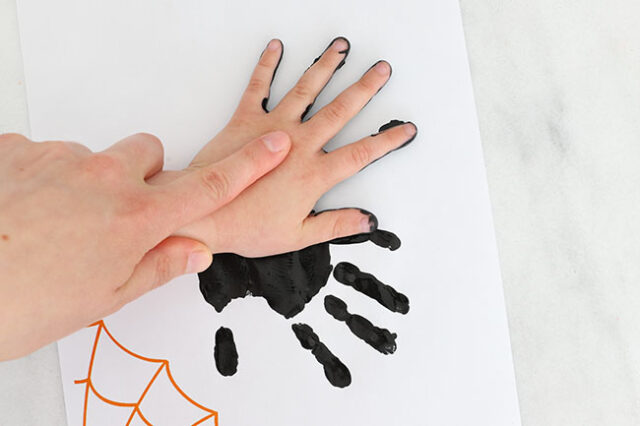 Second spider handprint stamping onto paper