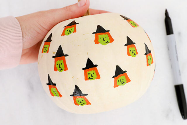 Drawing witch faces onto pumpkin