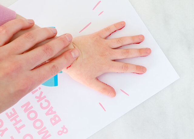 Hand stamping handprint onto rocket paper