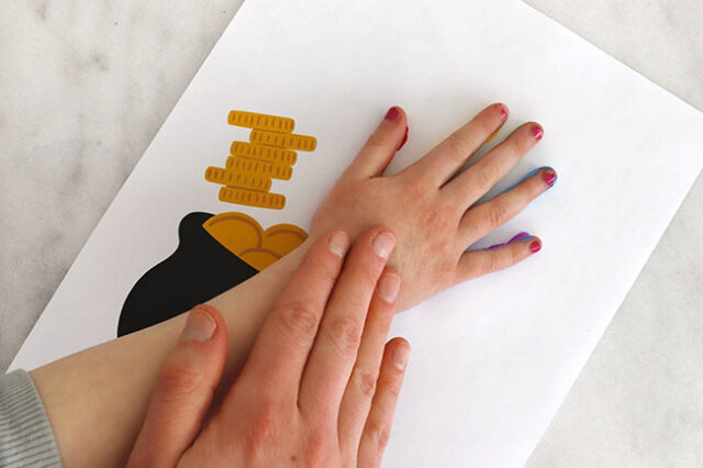 Printing hand onto rainbow cauldron