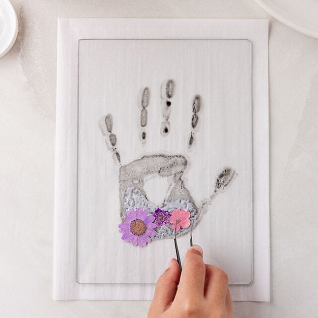Add pressed flowers to handprint